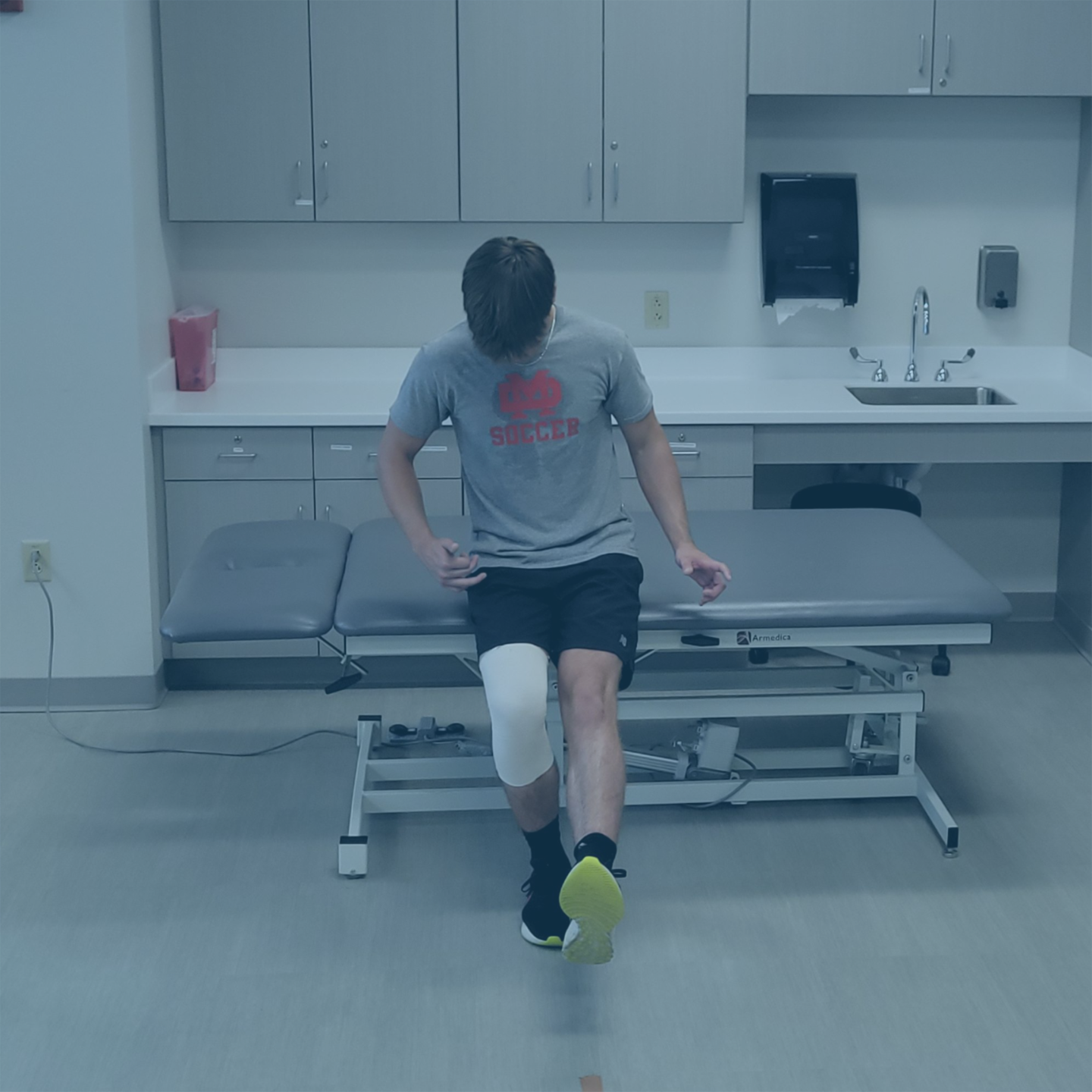 Athlete performing single-leg knee extension exercise during ACL rehabilitation progression
