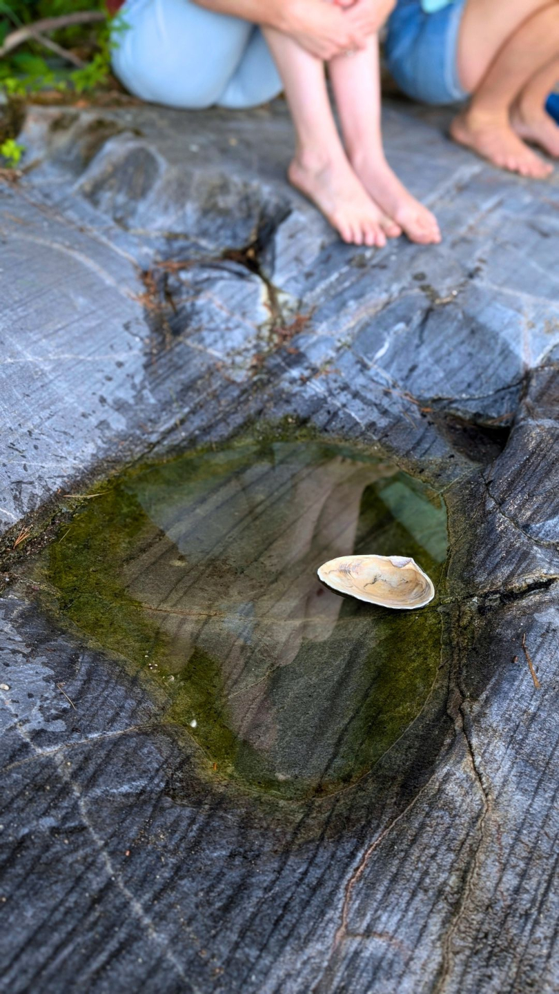 two people sitting barefoot on a rock with a small pool showing their reflection