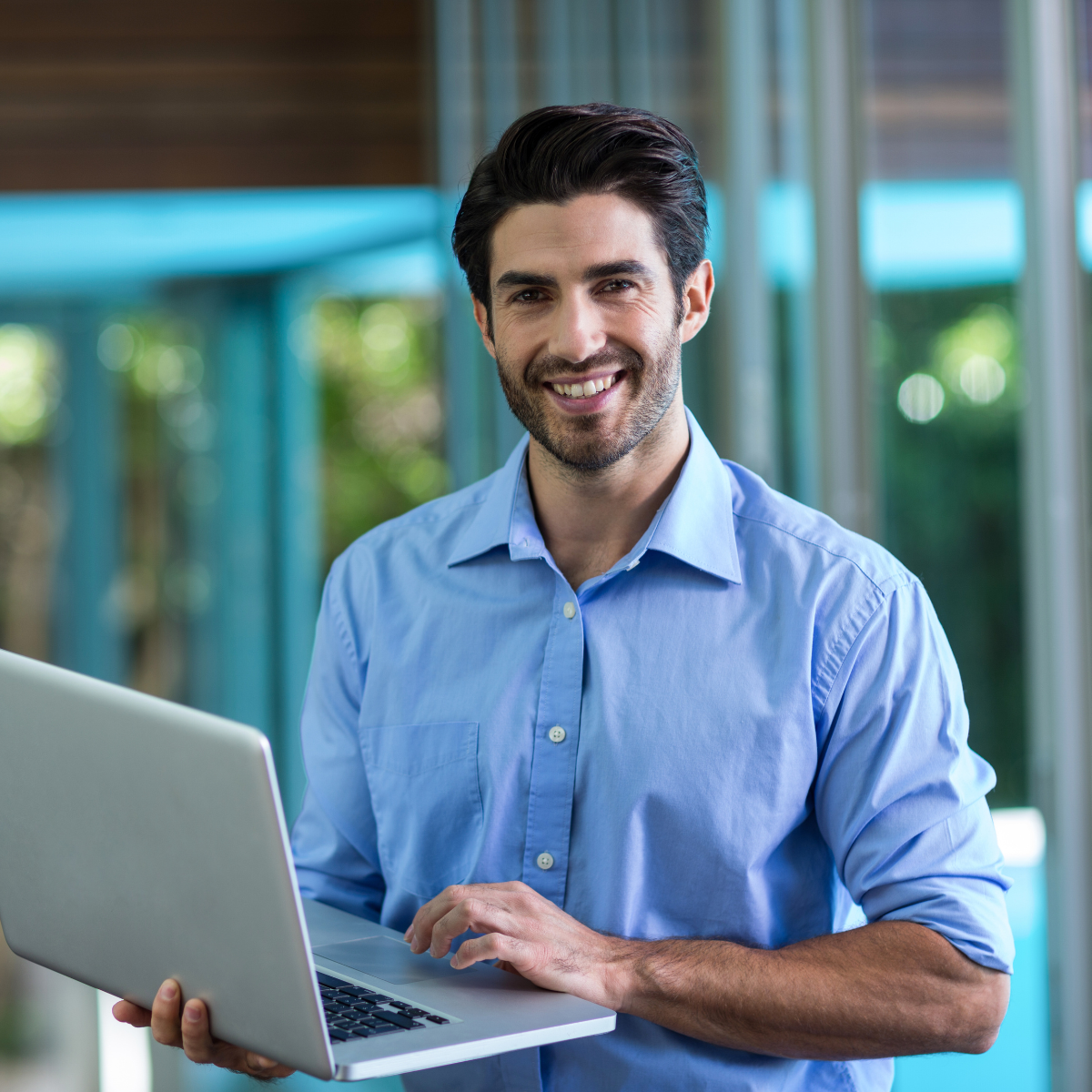 Professional man standing with a laptop in his hands smiling at the camera