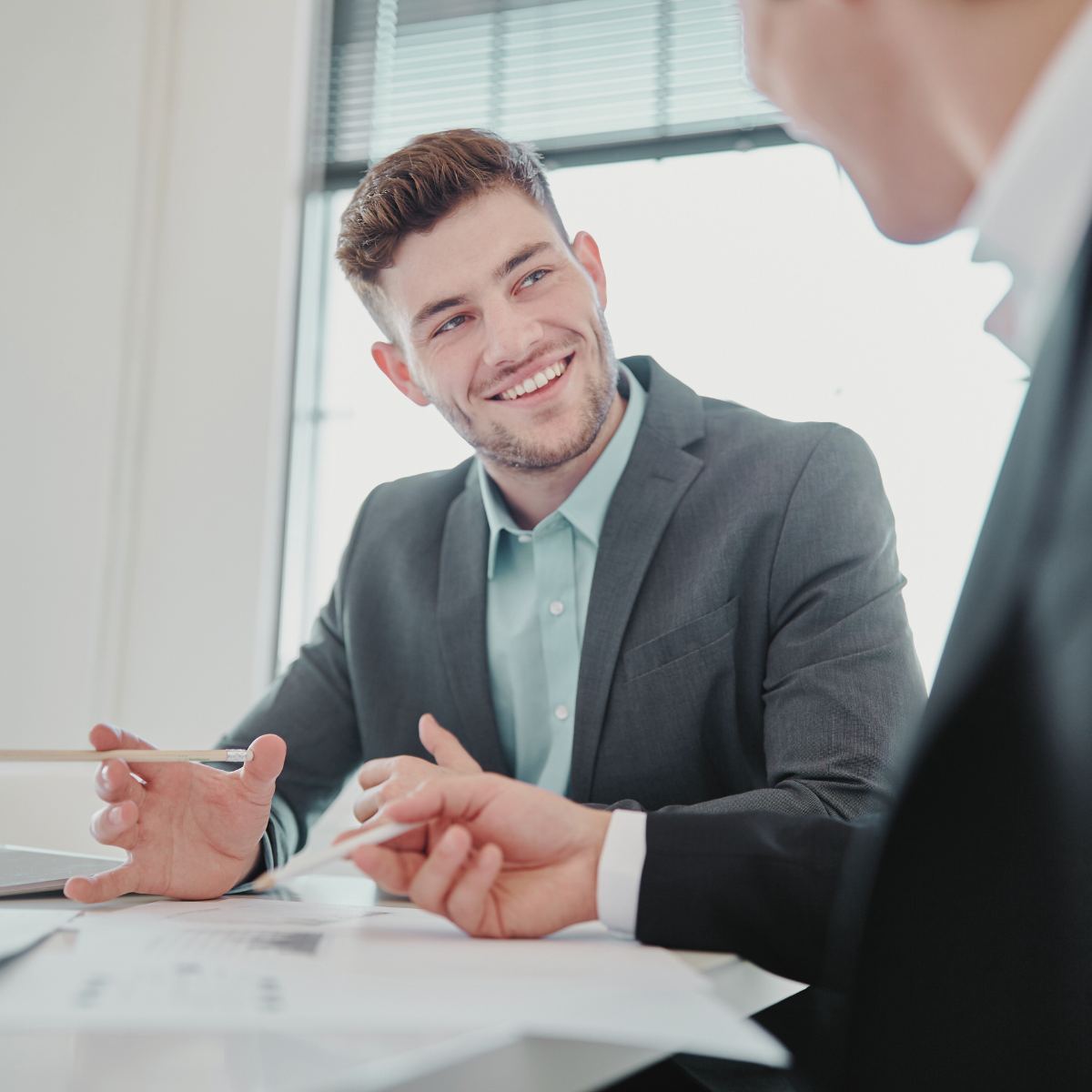 Professional man smiling at a colleague while reviewing reports