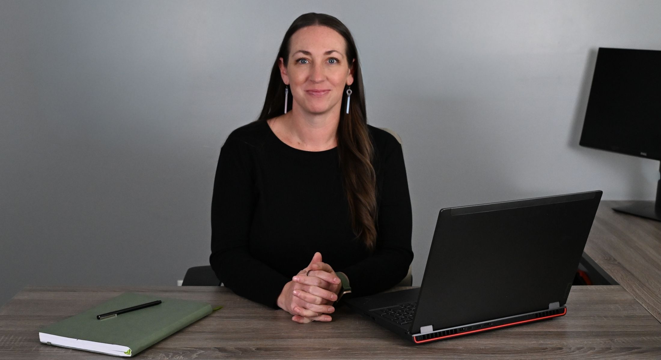 Jill Klott in black shirt sitting at desk with notebook, pen and laptop computer