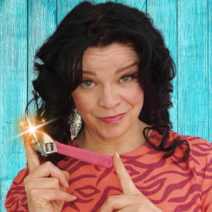 carita the mechanic headshot, wavy long brown hair, large siver earring and a pink wrench held with two fingers