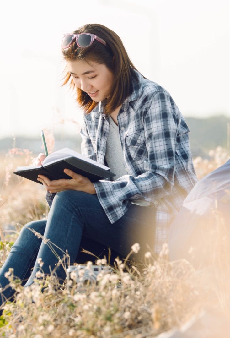 Woman journaling outdoors while reflecting on mindset and intentional living