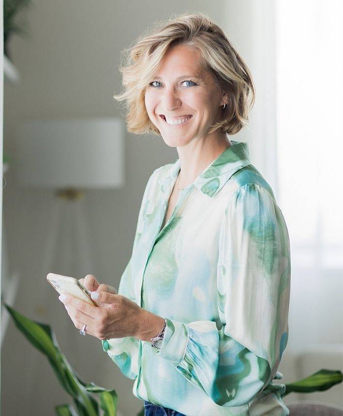Ciara Stockeland in green and white shirt with mobile phone in hands.