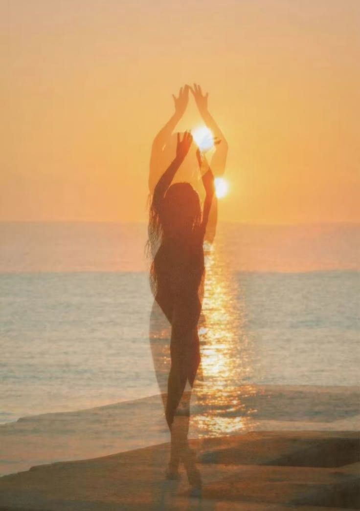 Woman at sunrise, arms raised