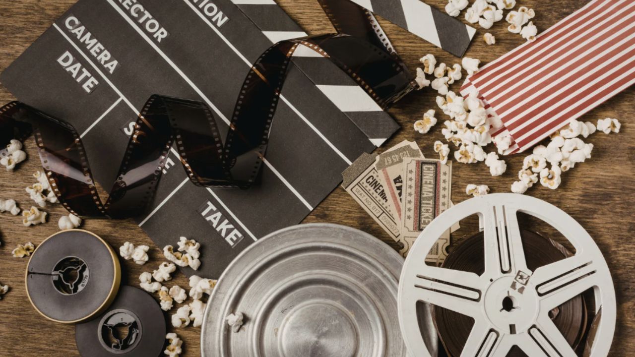 Image of film and movie props incluing popcorn, movie tickets, director's slate and film roll.