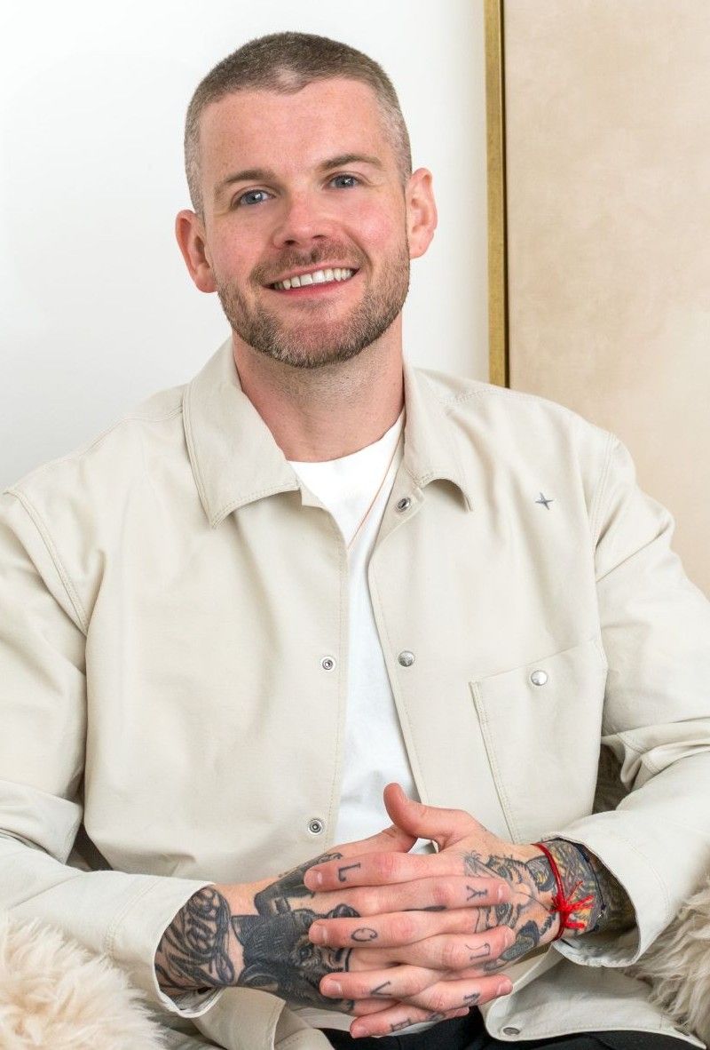 A photograph of Kyle Gray smiling with his hands in prayer
