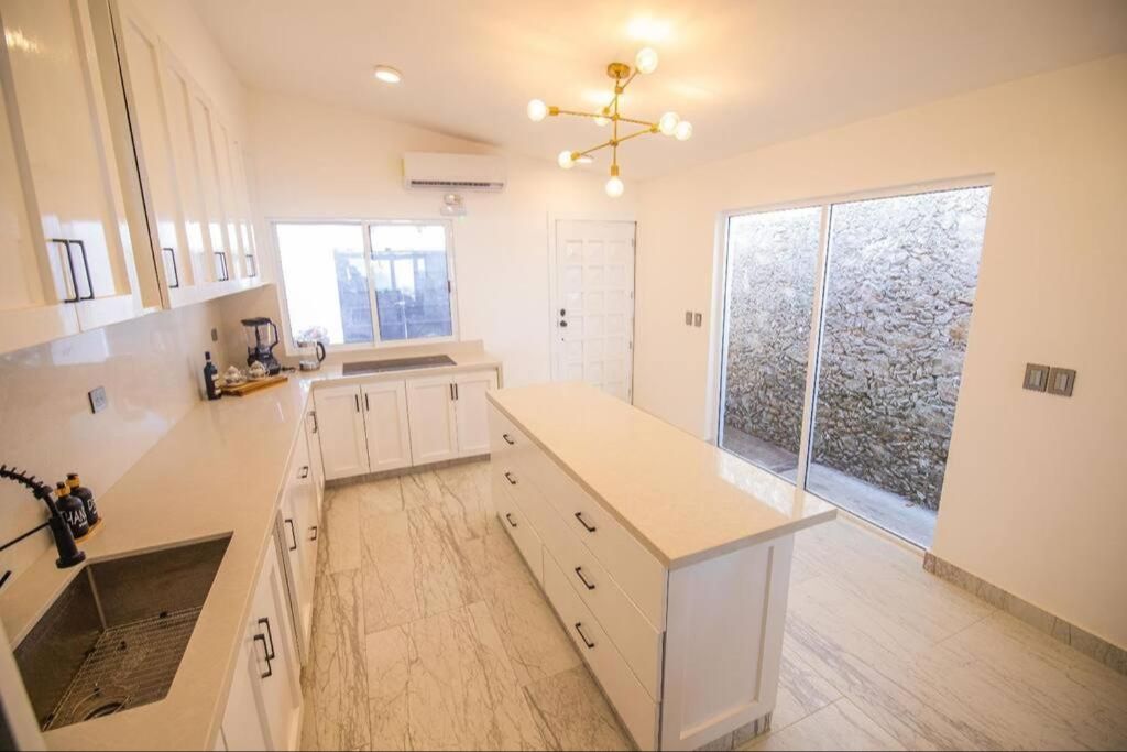 Brightly lit large kitchen with center island. Plenty of counter space and a large industrial sink.