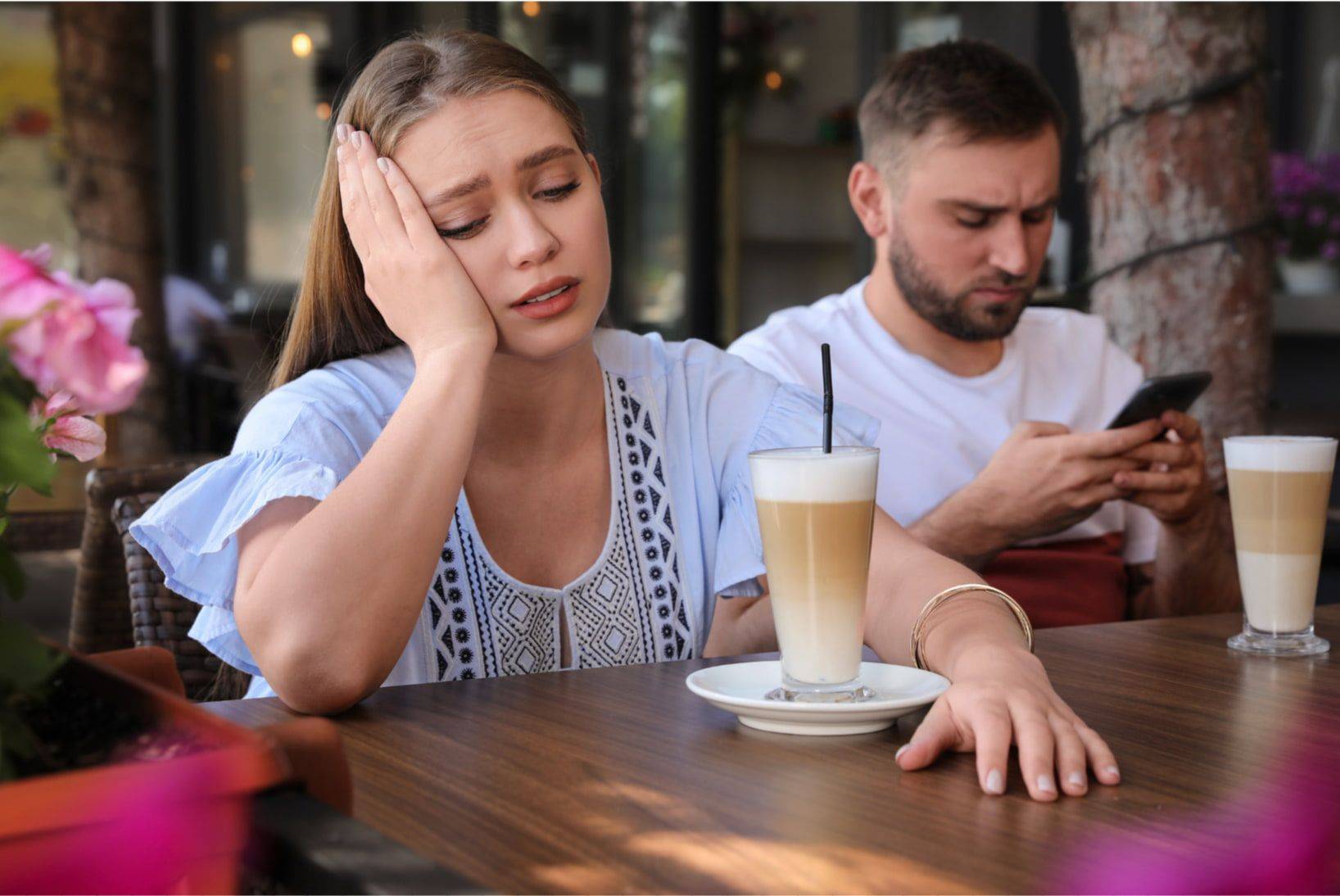 Frau mit Verlustangst sitzt nachdenklich neben ihrem Partner im Caf&eacute;
