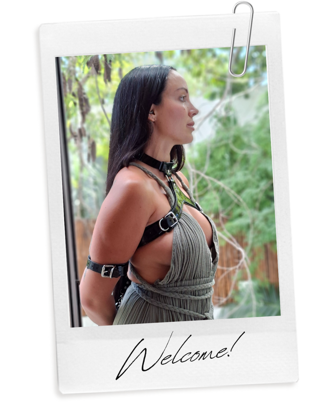 Julieta Chiara profile posing wearing a green dress and black leather chest and arm harness