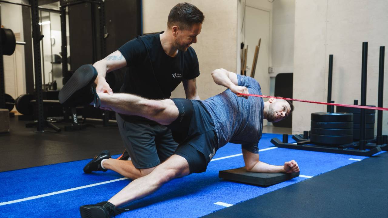 Fysioterapeutti ohjaa nuorelle urheilijalle harjoitetta kuntopallon avulla