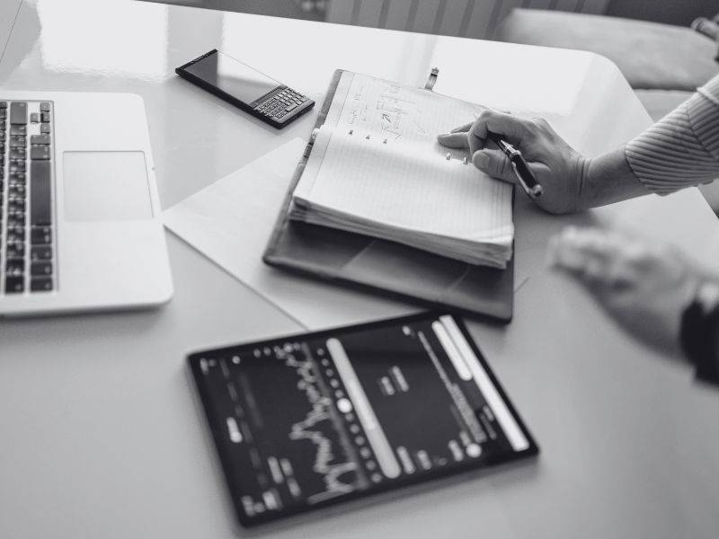 hands preparing to write in planner with financial chart beside the planner