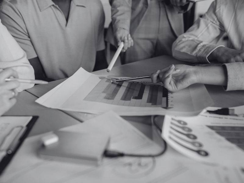 group of people gathered around a bar chart graphic displayed on a meeting table