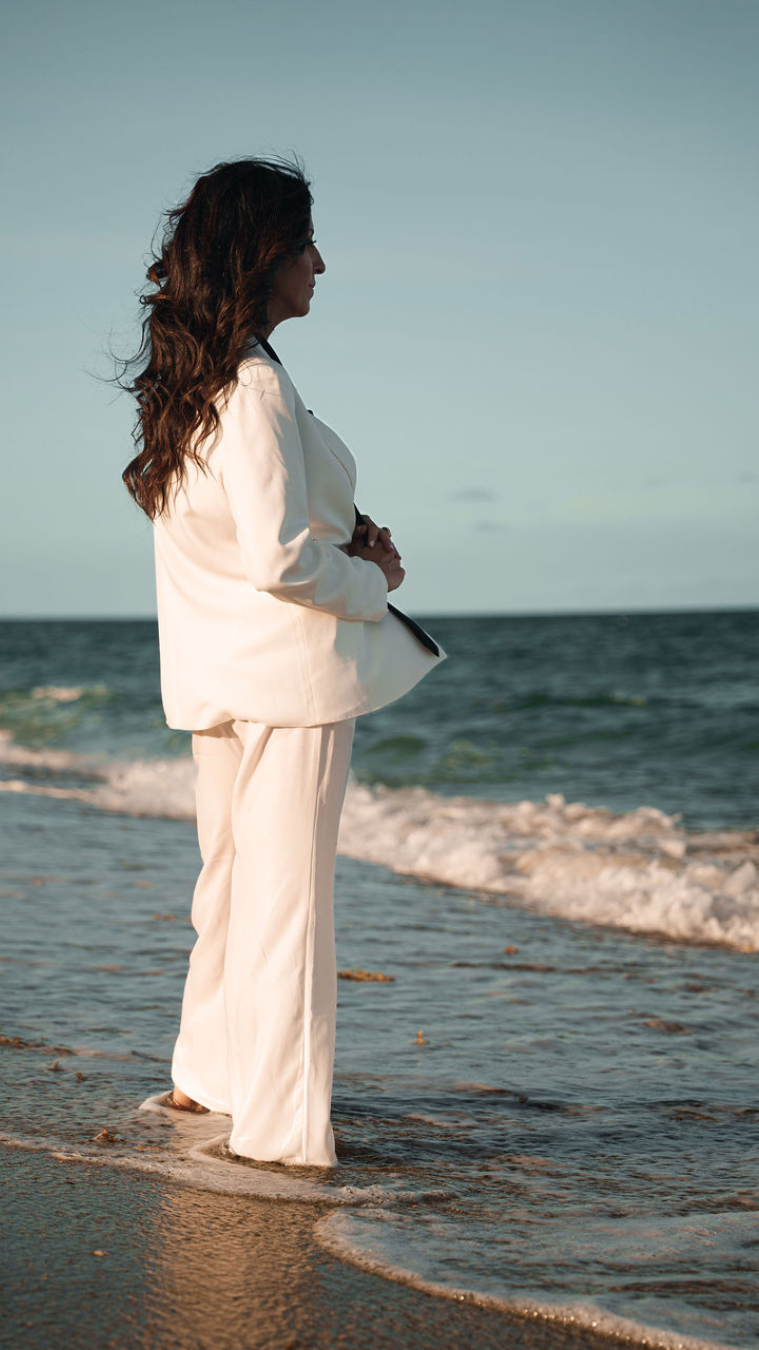 A woman leans on a stone ledge, gazing thoughtfully. 