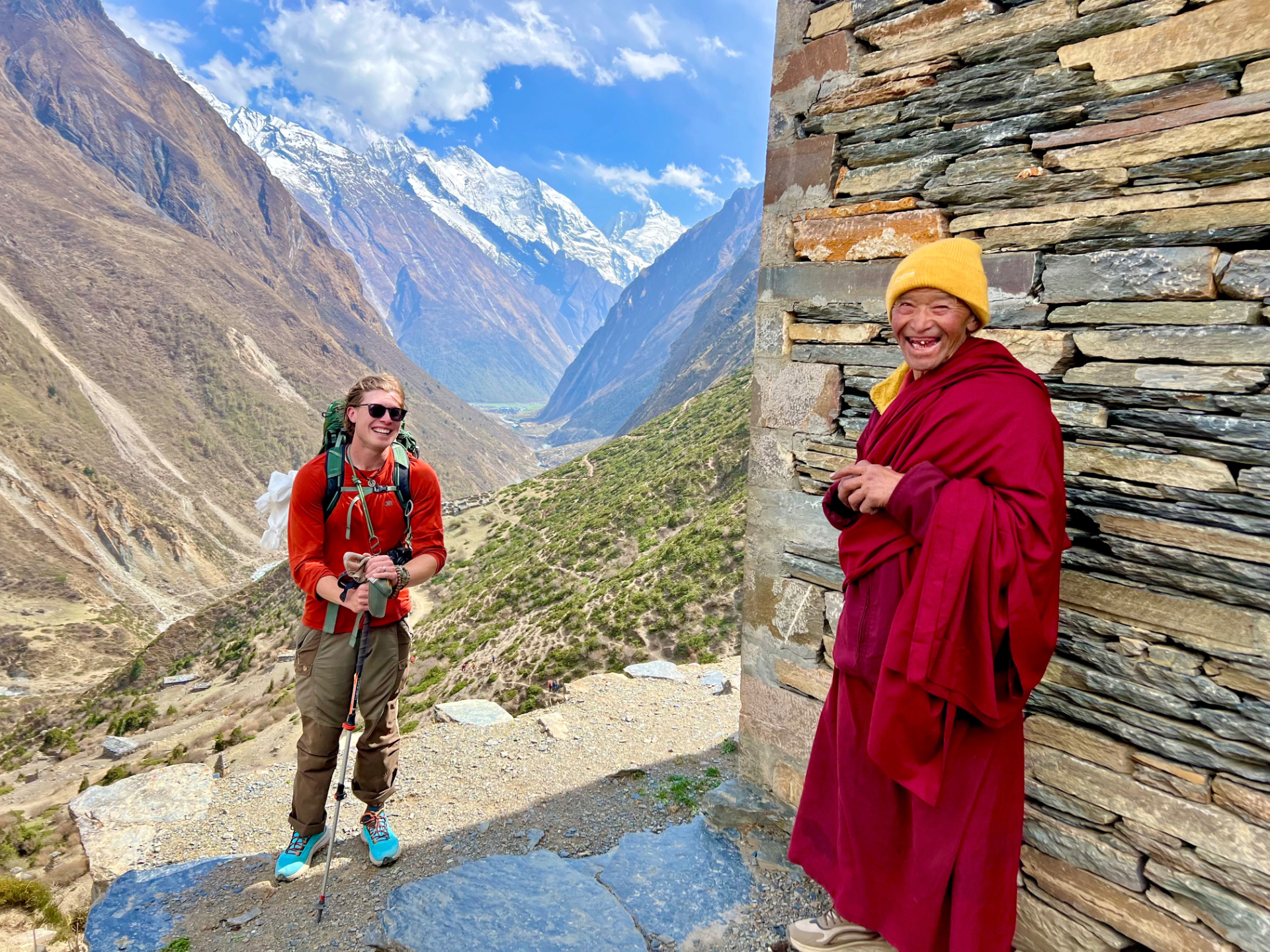 A pilgrim and a monk sharing a joyful moment on the trail to Mu Monastery, Tsum Valley, Nepal
