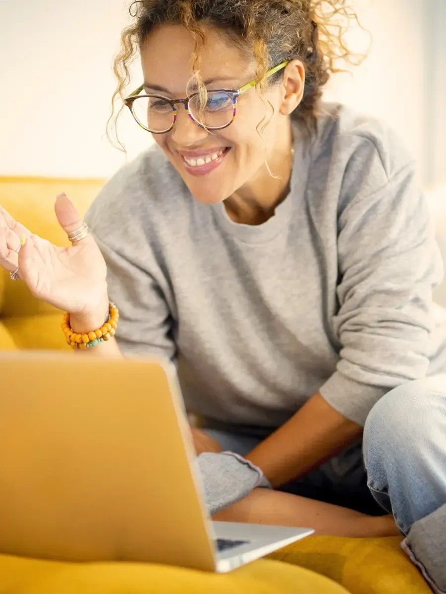 Woman smiling warmly at her laptop after registering for the Your Relationship with YOU live online self-nurturing workshop with Laura Rochelle