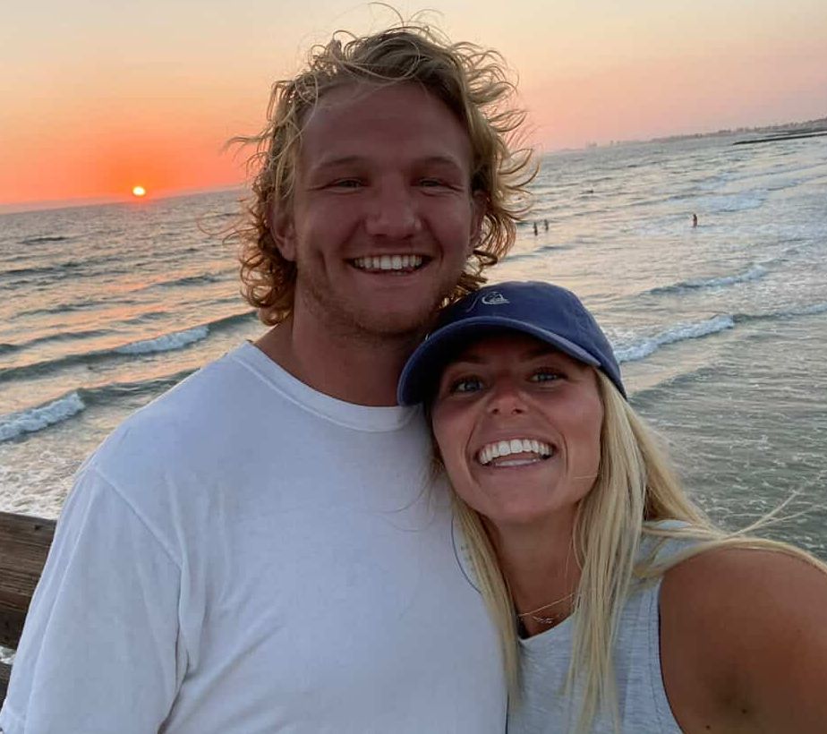 a man and woman smiling in front of the ocean.