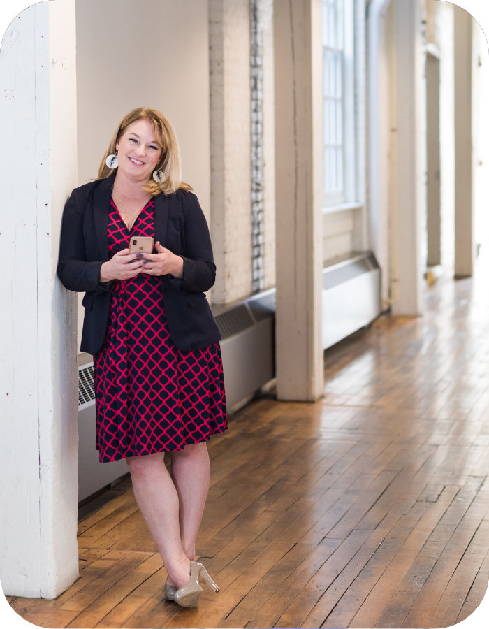 Brand Messaging Strategist Jen Liddy standing in hallway, leaning against wall