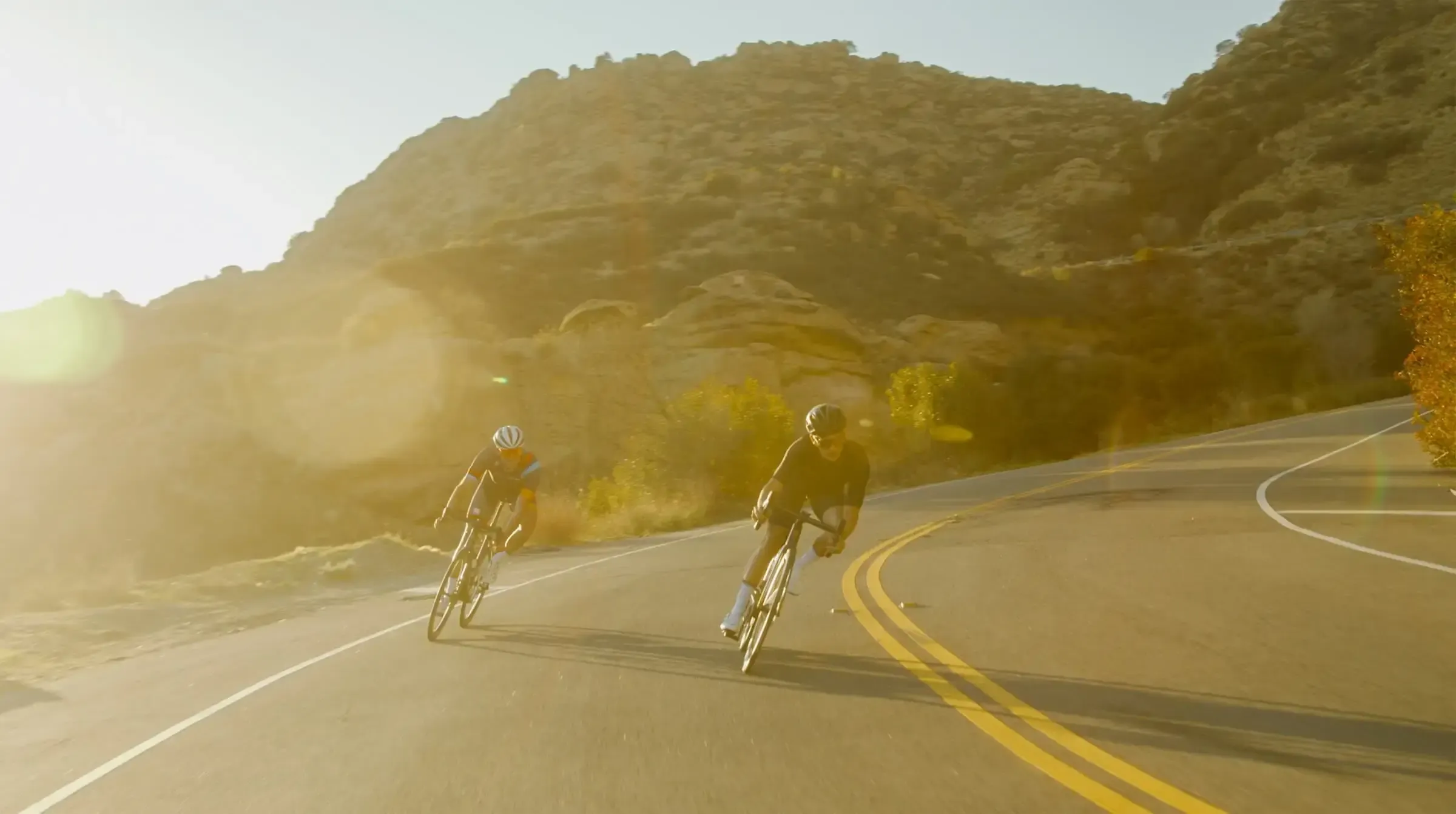 Cyclists descending a mountain road at sunrise