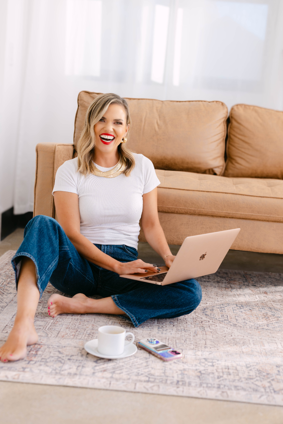 Laura Conley sitting on a couch laughing, holding her phone