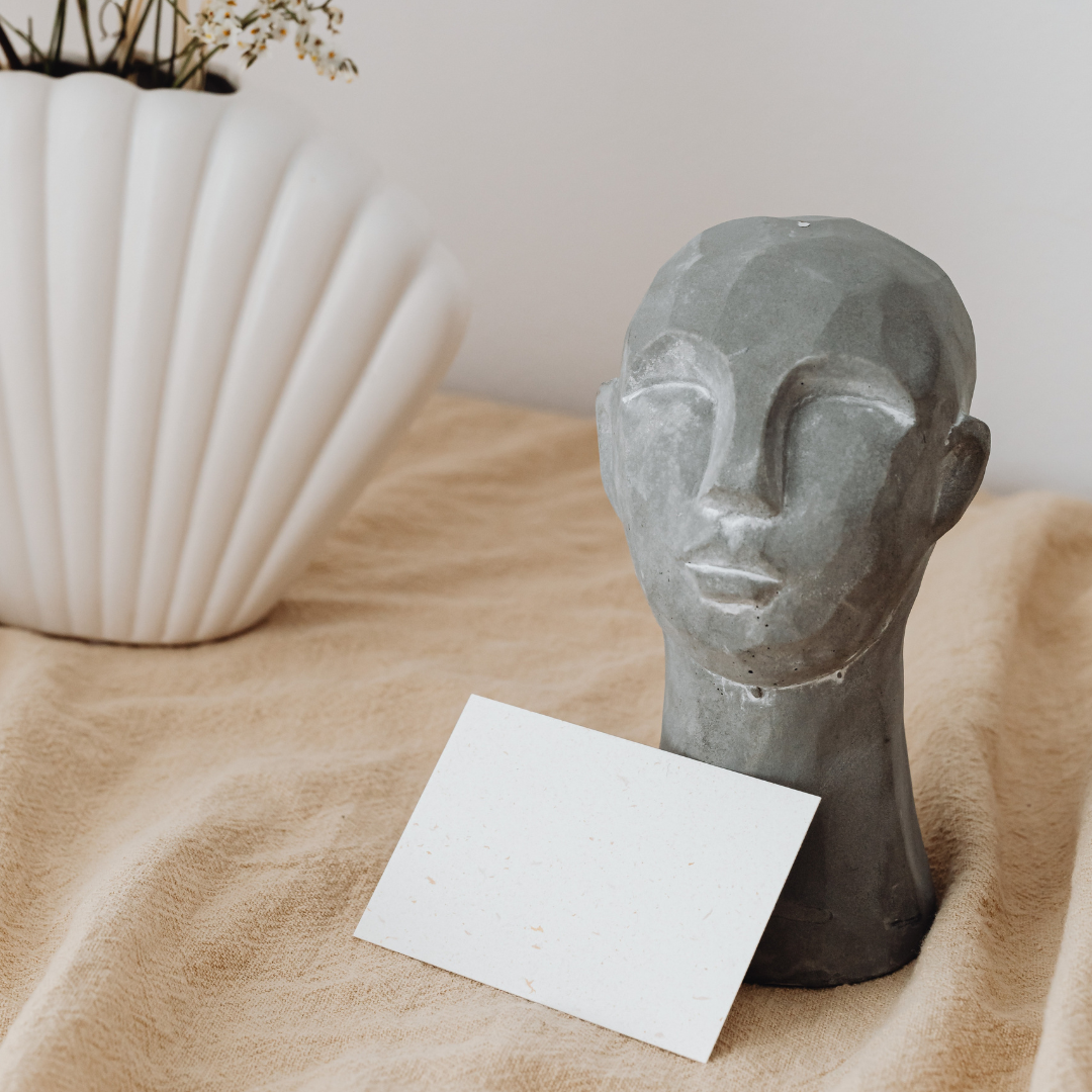 sculpture of a head on a table with a notecard