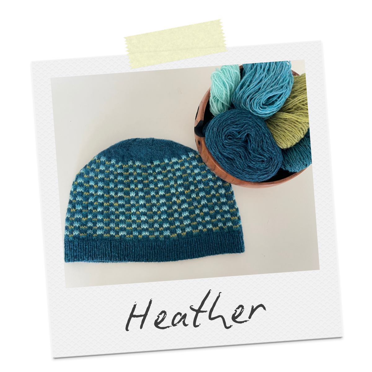 Polaroid with the word Heather written on it. The photo shows a colourwork beanie in various shades of blue with a pop of yellow. Next to it is a bowl of yarn.