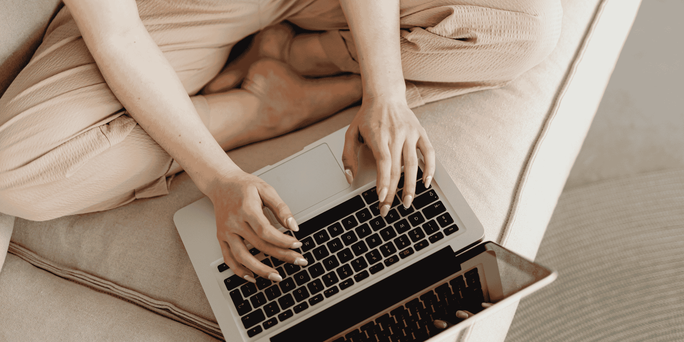 Kvinne som skriver på laptop i sofaen