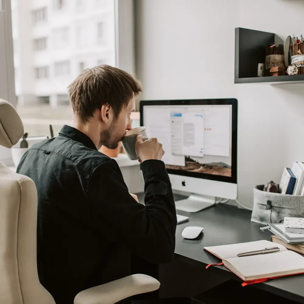 Man drinking coffee behind desk