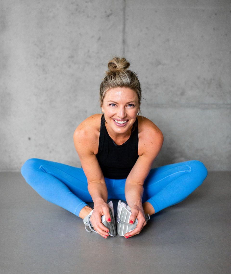 Kate stretching for a workout in a concrete gym