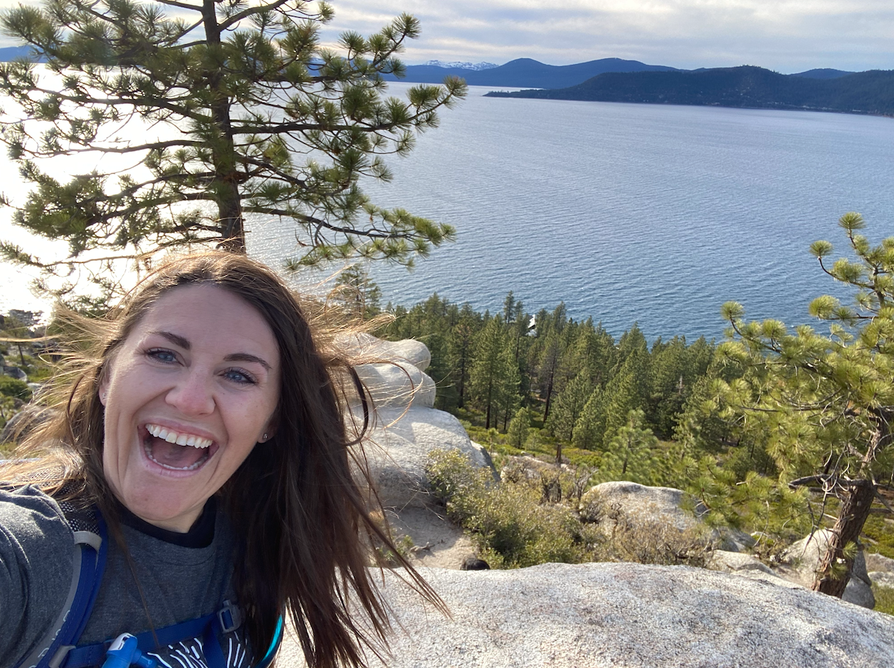 Chelsey laughing on a windy overlook above Lake Tahoe