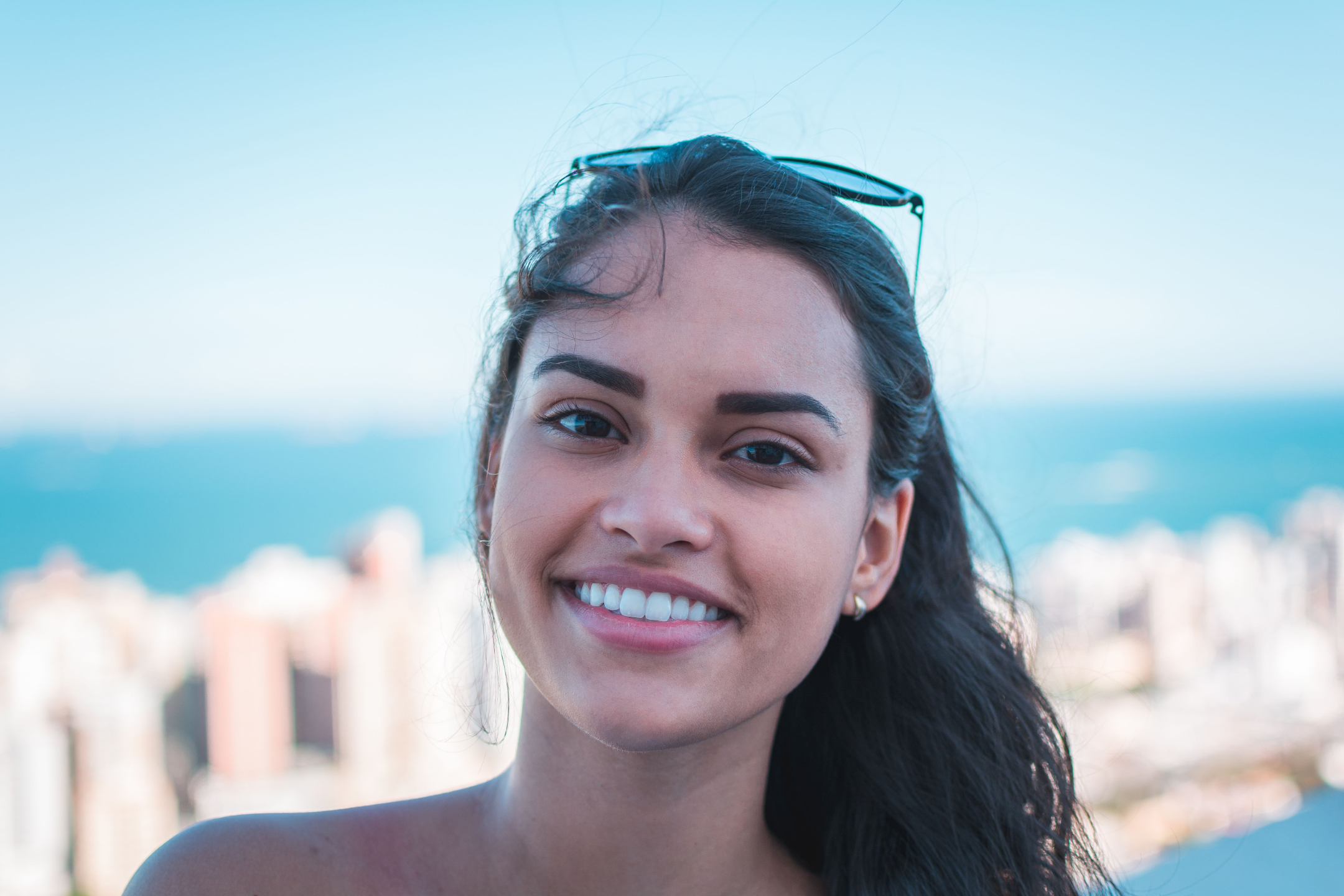 Young woman smiles with sunglasses on her head.