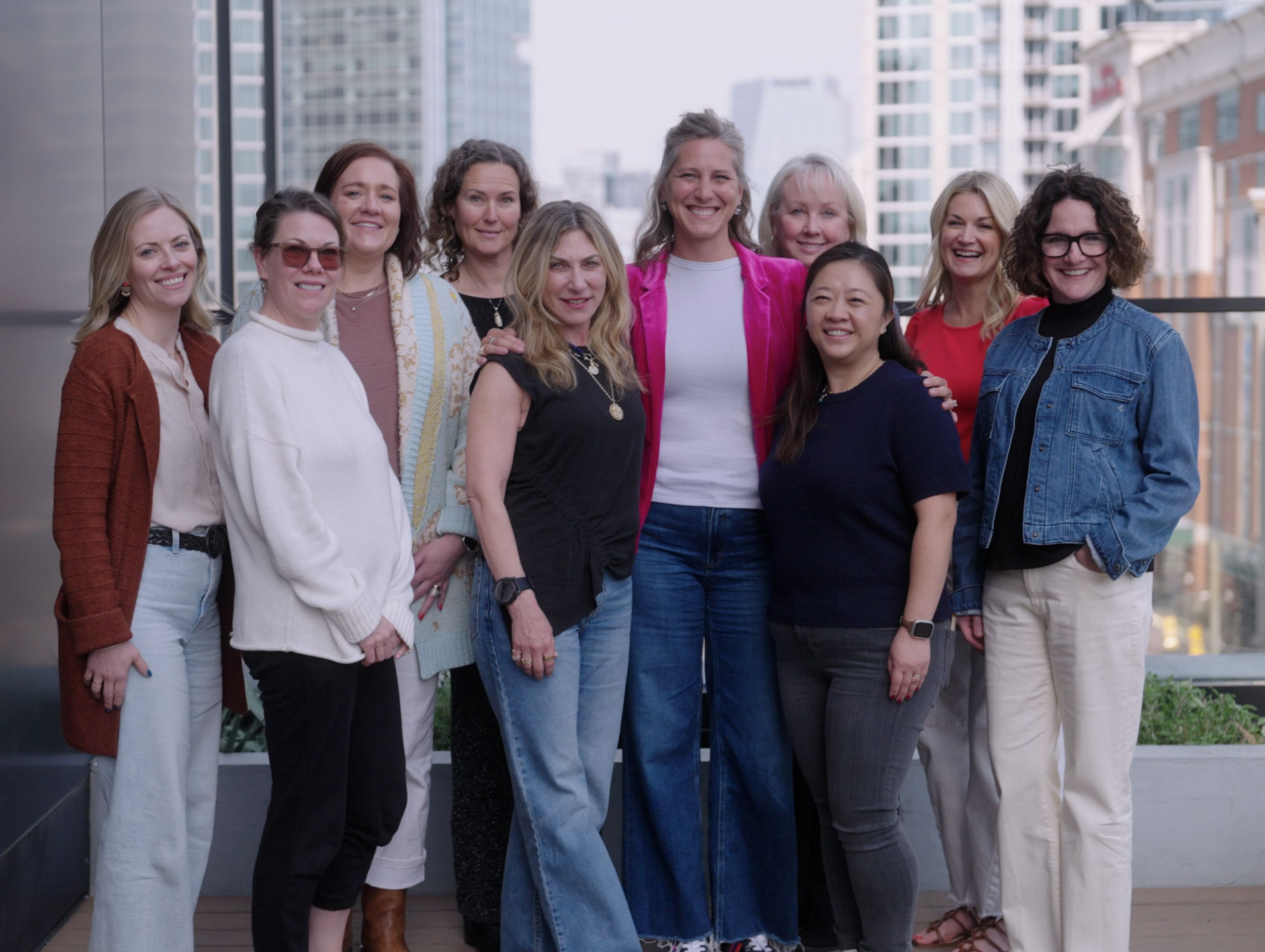 A group of professional woman stand outside in an urban setting.