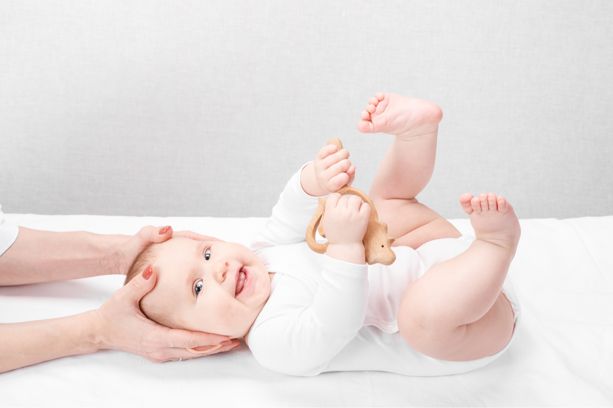 Baby lying down with mother gently supporting their head during baby flat head and torticollis care.