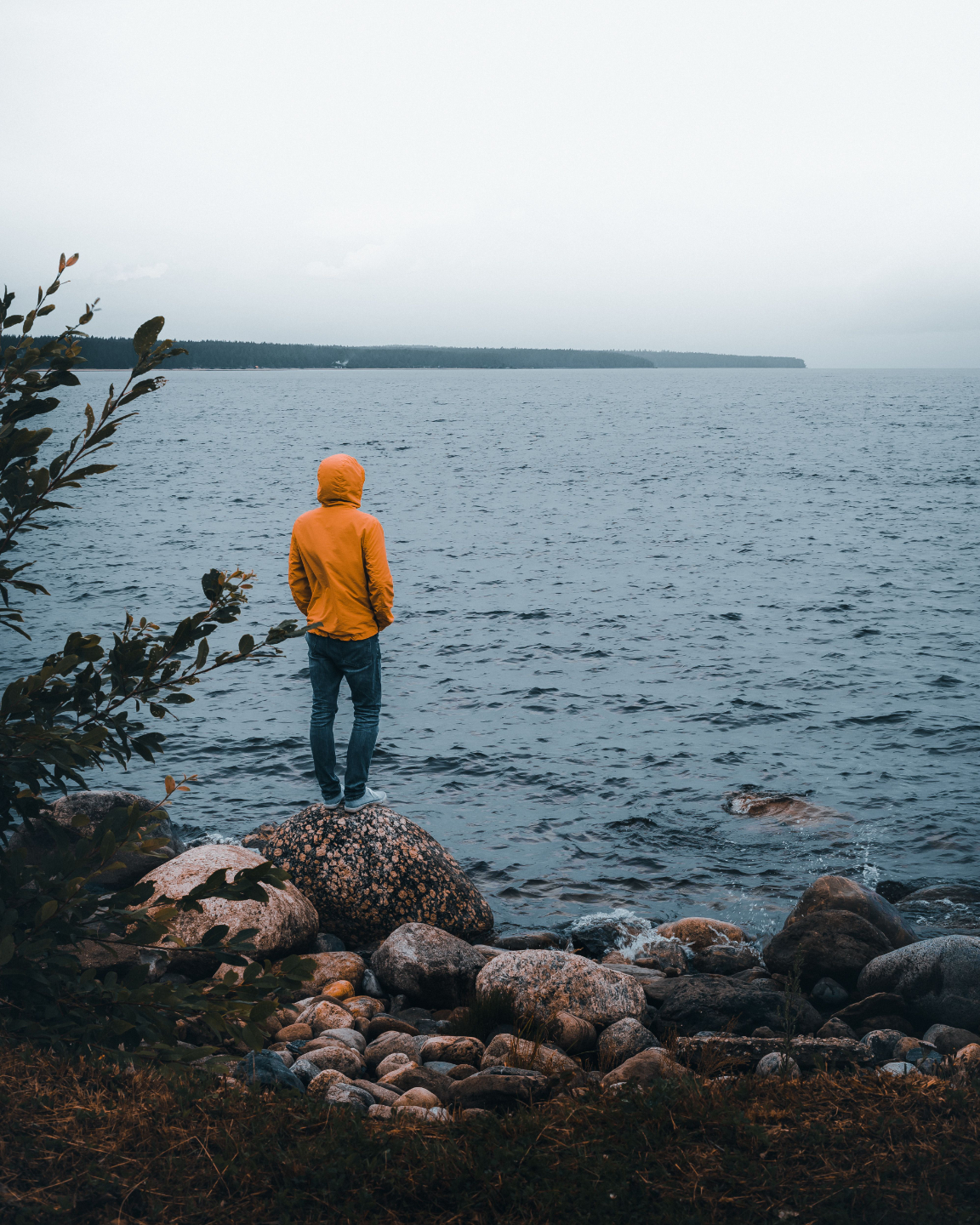 Man standing at the edge of the sea on a gloomy day.