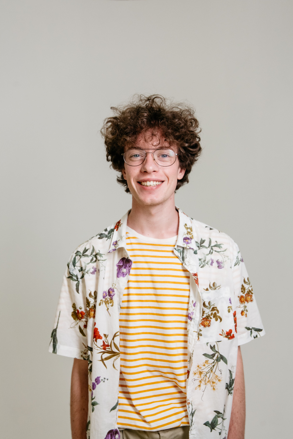 Young man smiles wearing glasses.