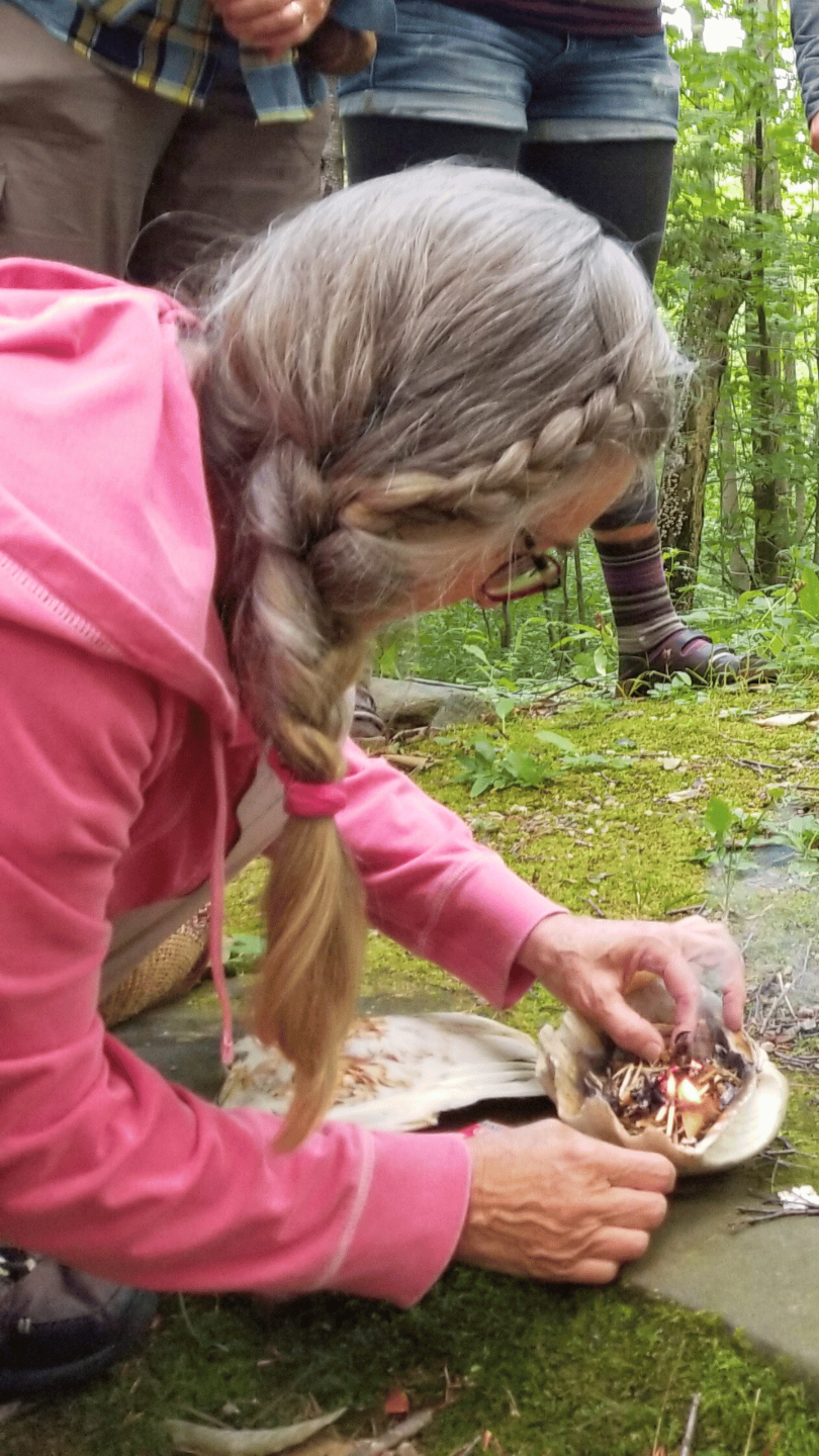 dorothy stone lightening a small fire in a shell with people standing near by