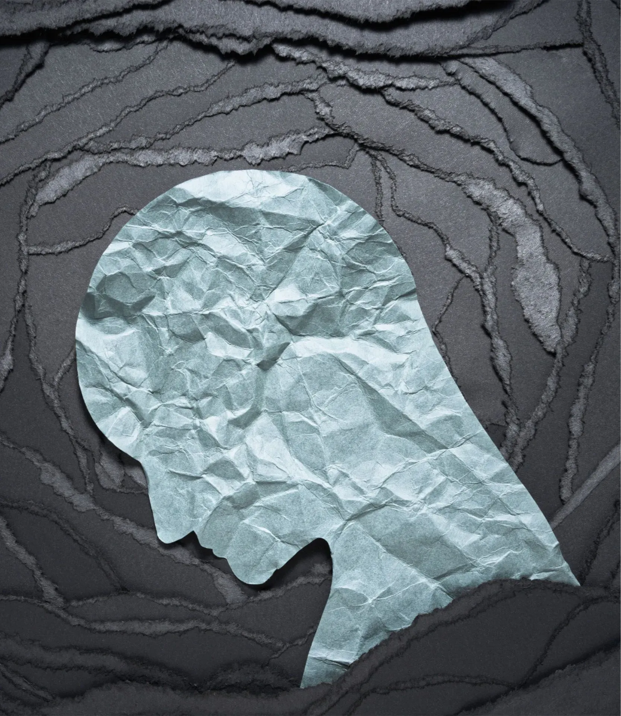 A silhouette of a person with depression made out of crumpled paper