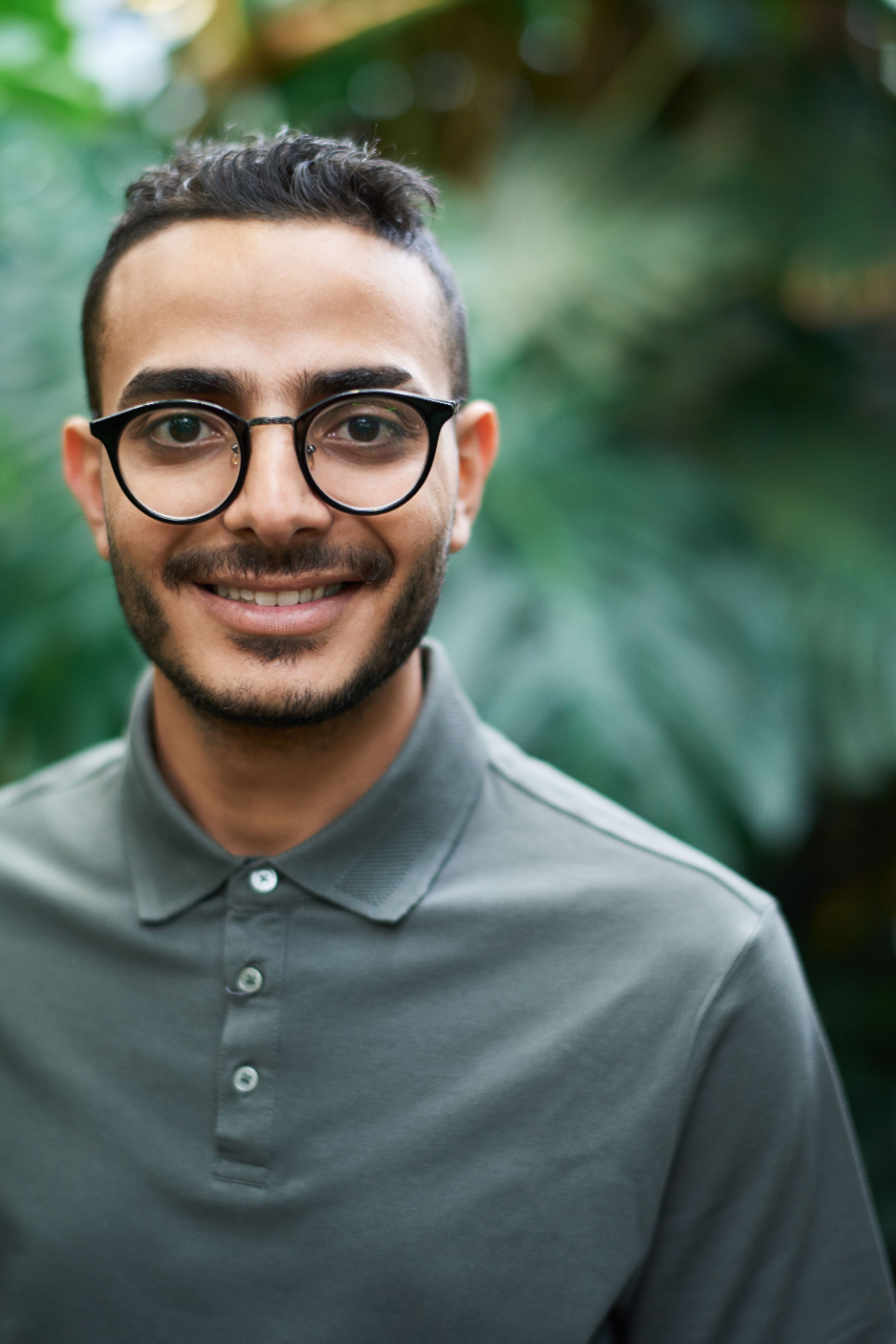 Young man with glasses smiles with content.