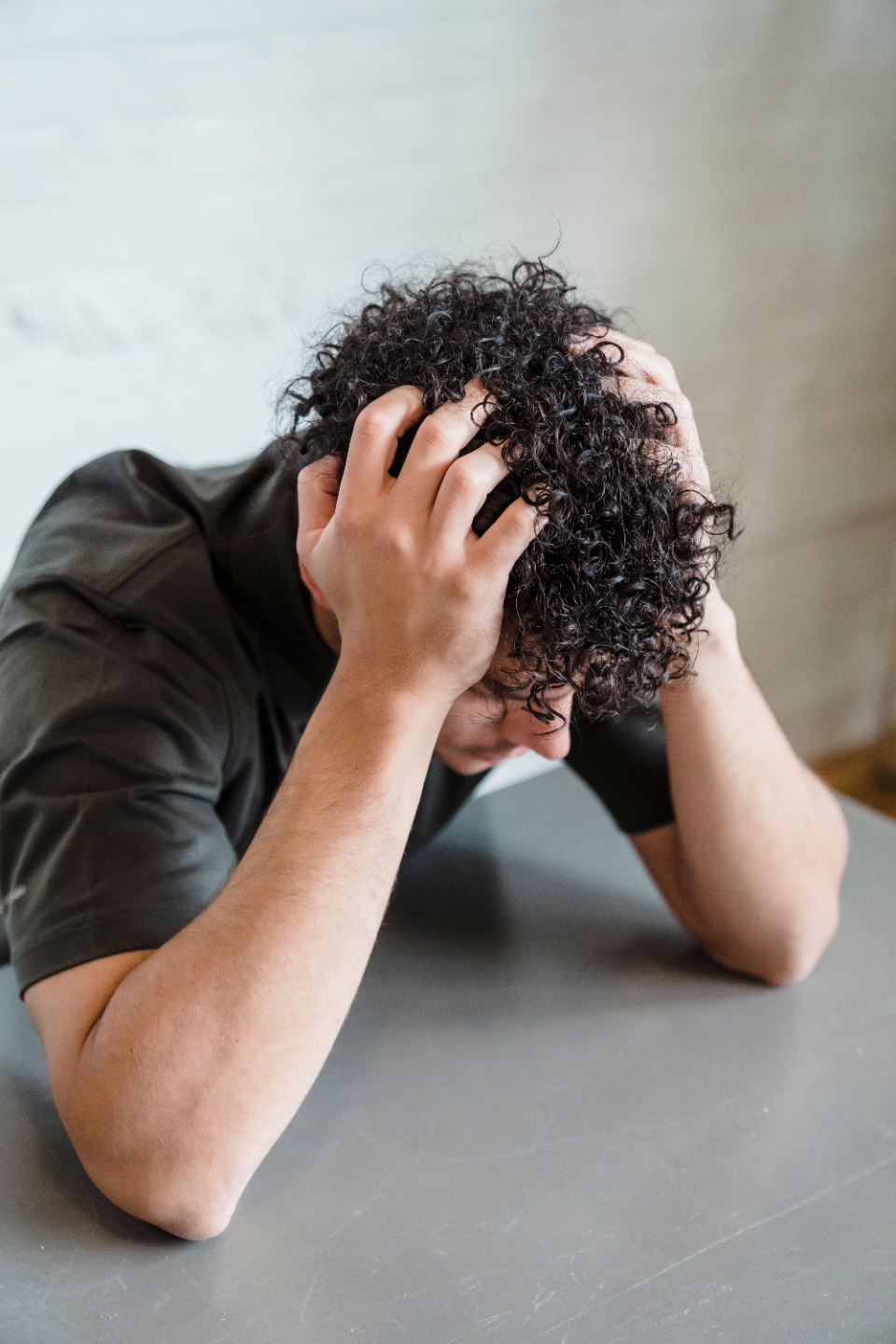 Young man with curly hair puts is hands on his head in frustration.