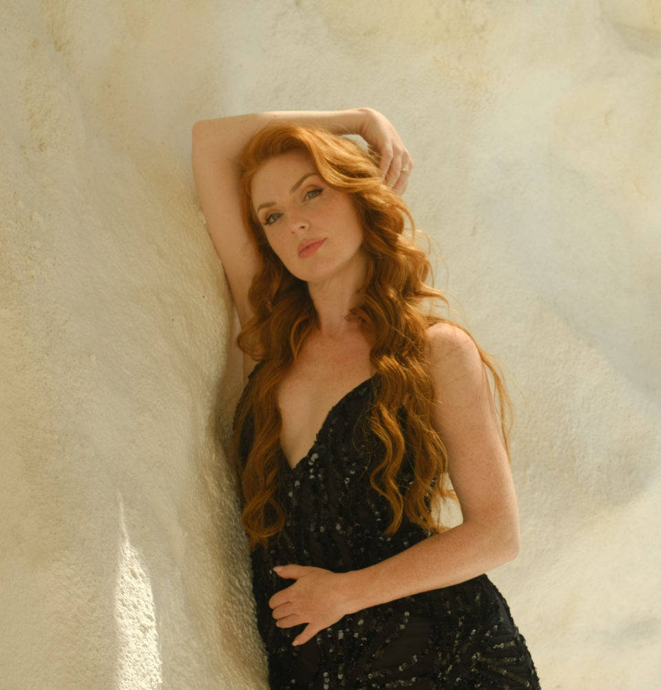 Michelle Pound with red hair in a black lace bodysuit in a Polaroid-style Welcome photo for the About Me section of LinkintheBio