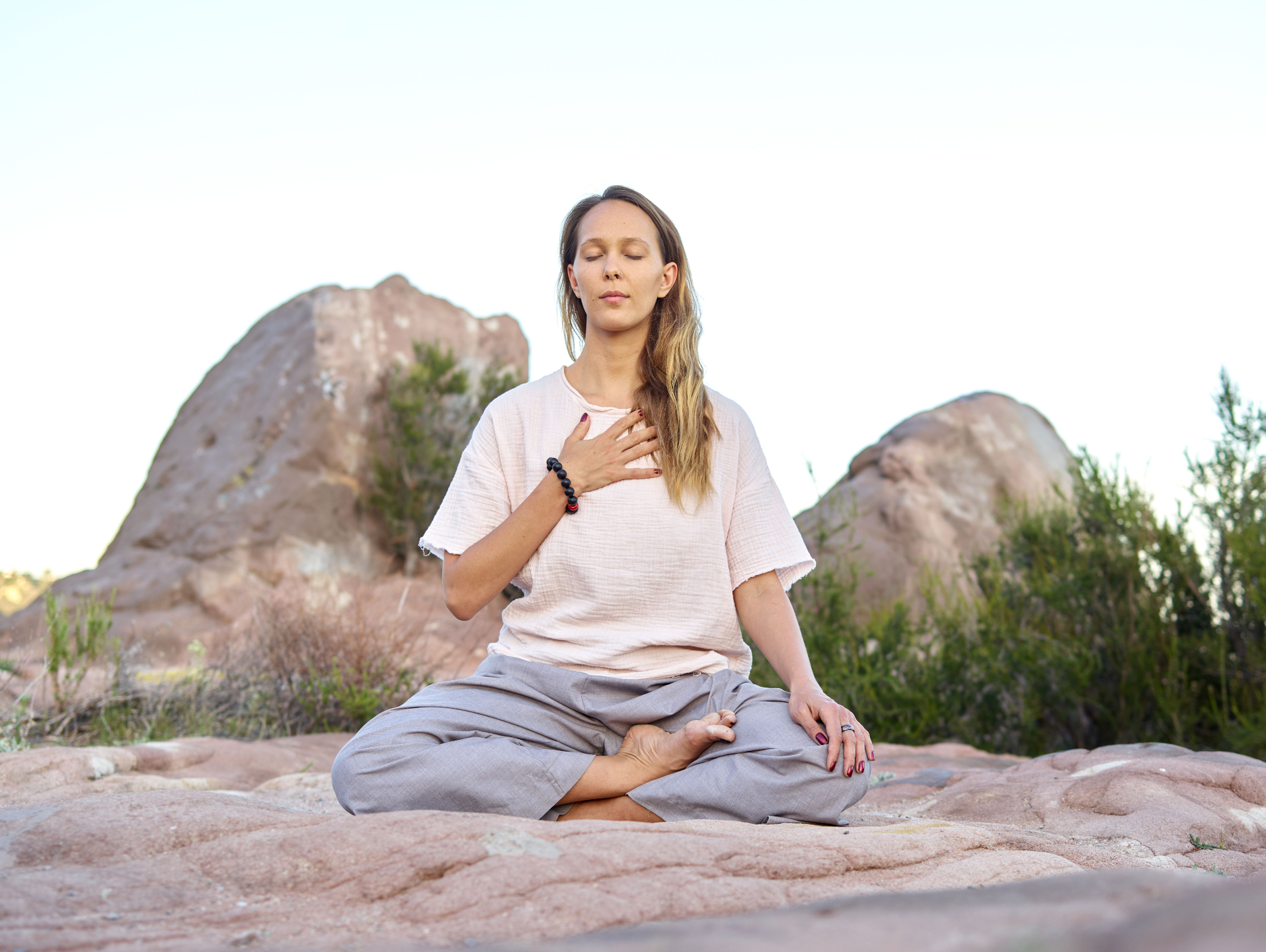 A woman sits in meditation in the desert.