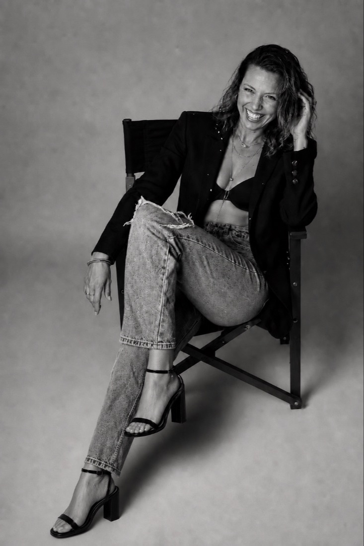 Andrea Crowder seated in a director's chair, laughing