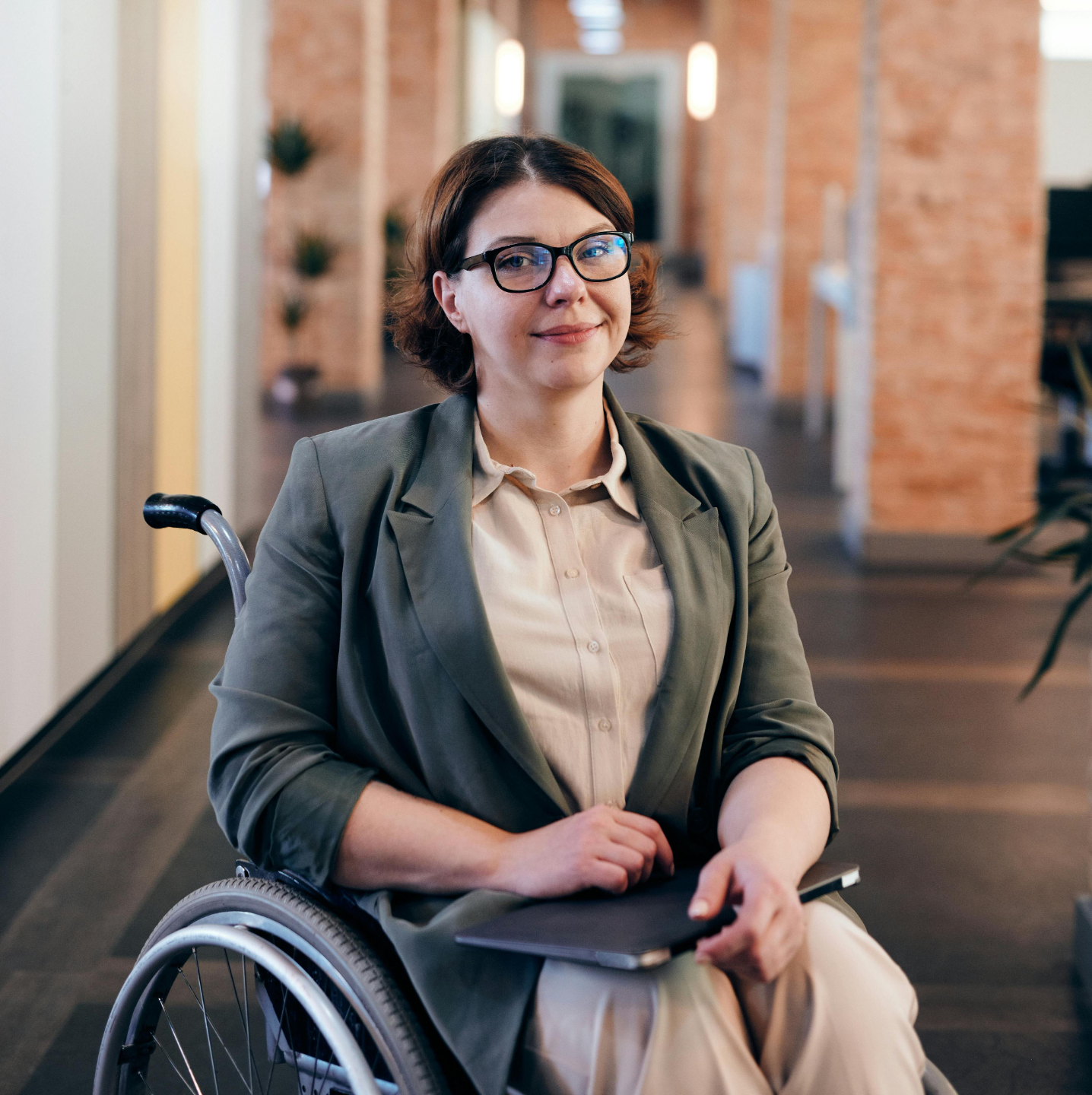 A professional who uses a wheelchair holding a tablet in an office