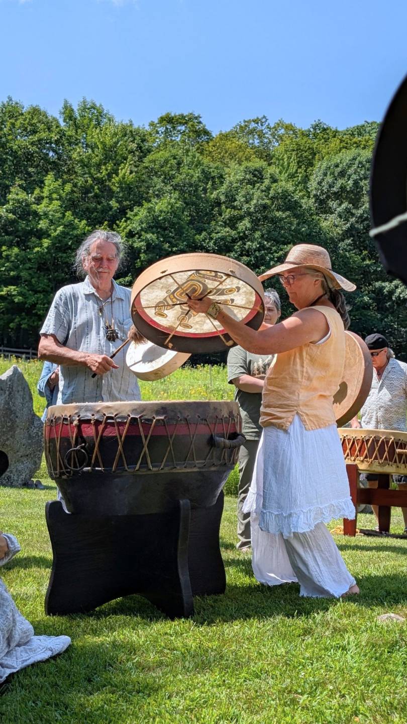 Zacciah Blackburn and Dorothy Stone playing drum in a field with other people