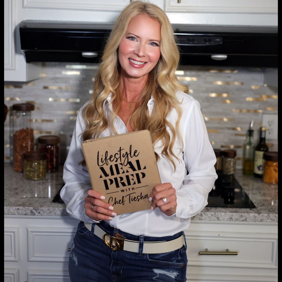 Chef Tiesha Taylor — Culinary Wellness Expert holding her cookbook in the kitchen