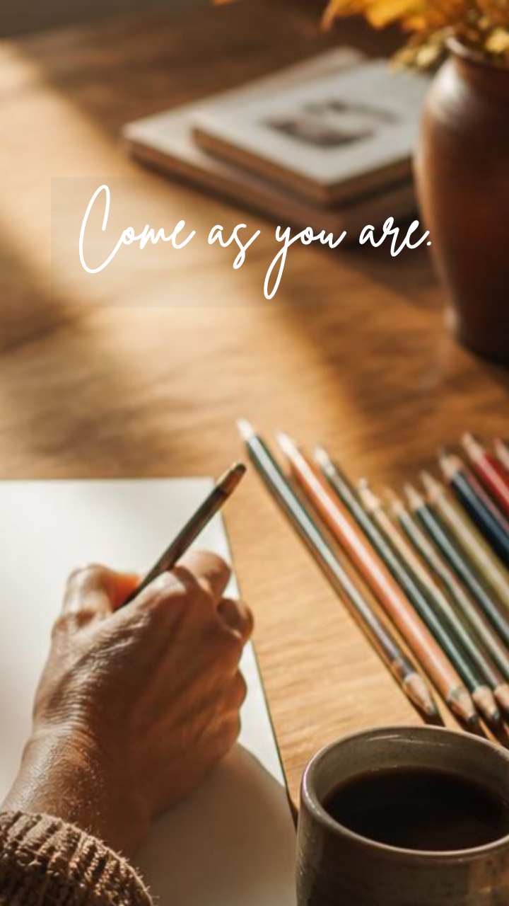Woman's hand writing on table with words top, center 'Come as you are.'