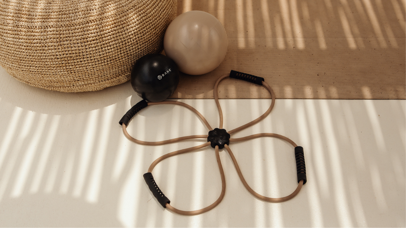 Pilates reformer exercise band next to 2 pilates balls