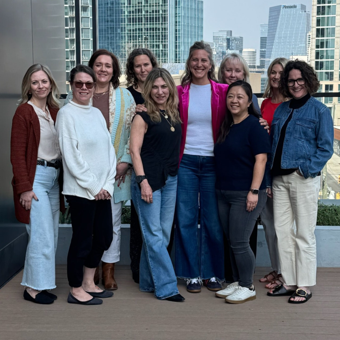 Ciara Stockeland with a group of coaching students standing on a rooftop patio with a city skyline behind them.