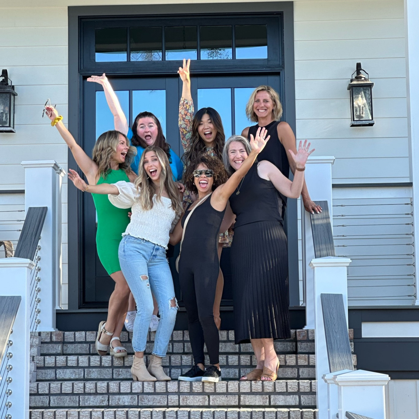 Group of women standing in celebratory group on stairs of front porch.