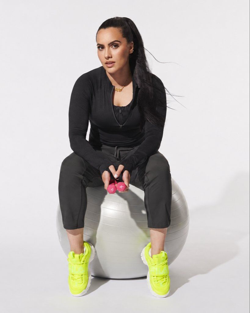 Laiba Zaid sitting on a stability ball holding pink dumbbells
